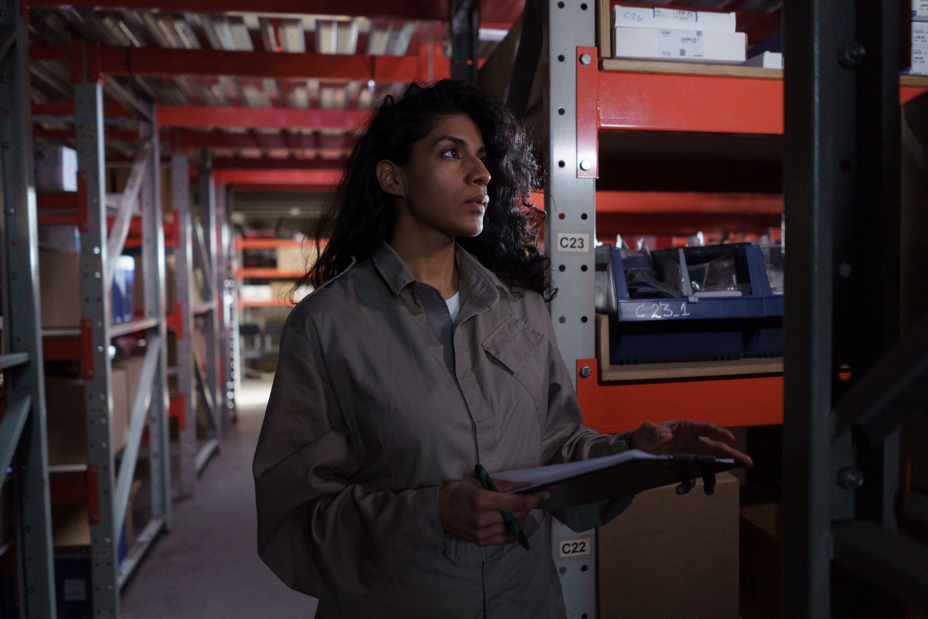 Female warehouse worker checking inventory in an industrial storage facility.